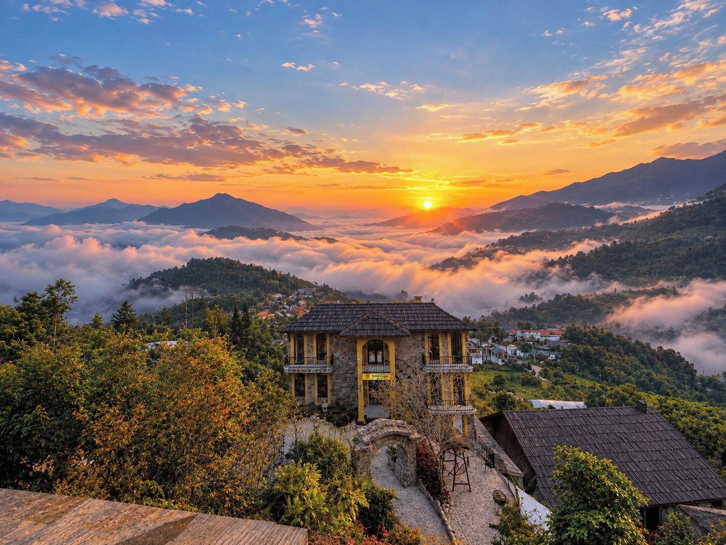 A stone building with a balcony, surrounded by lush greenery and mountains in the background.