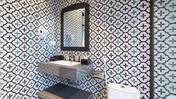 Un baño con pared estampada, un espejo, un lavamanos y un inodoro.