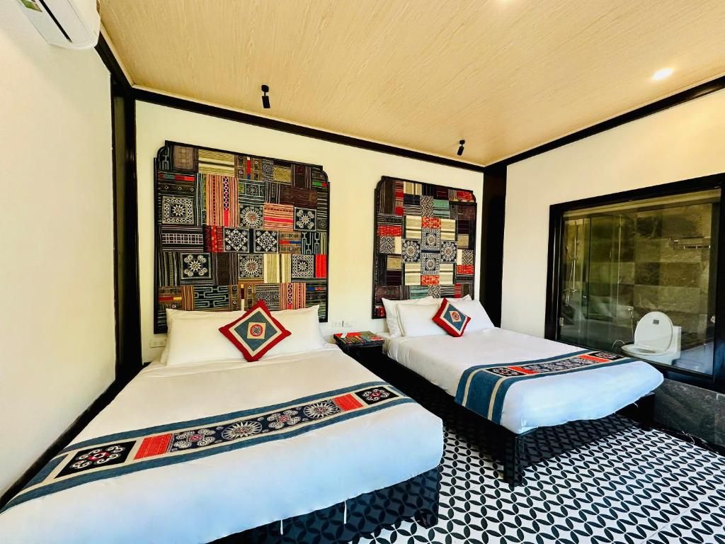 Una habitación de hotel con dos camas, un cabecero estampado, un ventanal grande y un diseño geométrico en el suelo.