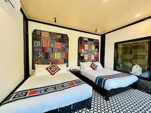 Una habitación de hotel con dos camas, un cabecero estampado, un ventanal grande y un diseño geométrico en el suelo.