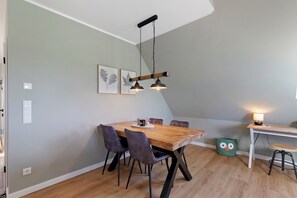 Een eetruimte met een houten tafel, vier stoelen en hanglampen.