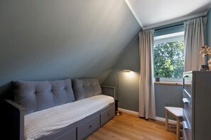 Un dormitorio con cama, escritorio, silla y ventana con cortinas.
