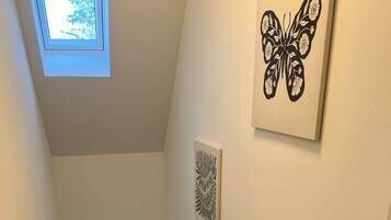 Un escalier avec une rampe, une lucarne et des œuvres d’art accrochées aux murs.