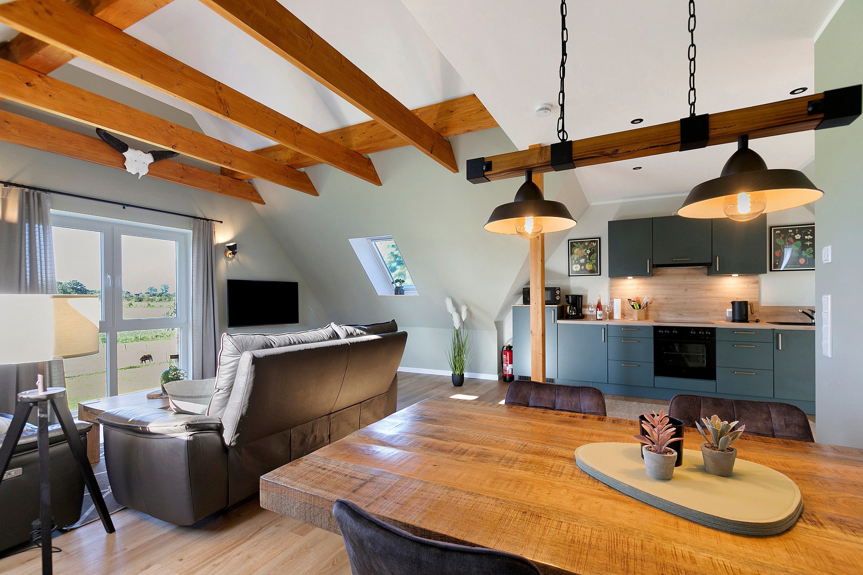 Ein modernes Interieur mit einem Holzespeisetisch, einer Couch und einer Küchenzeile mit blauen Schränken.