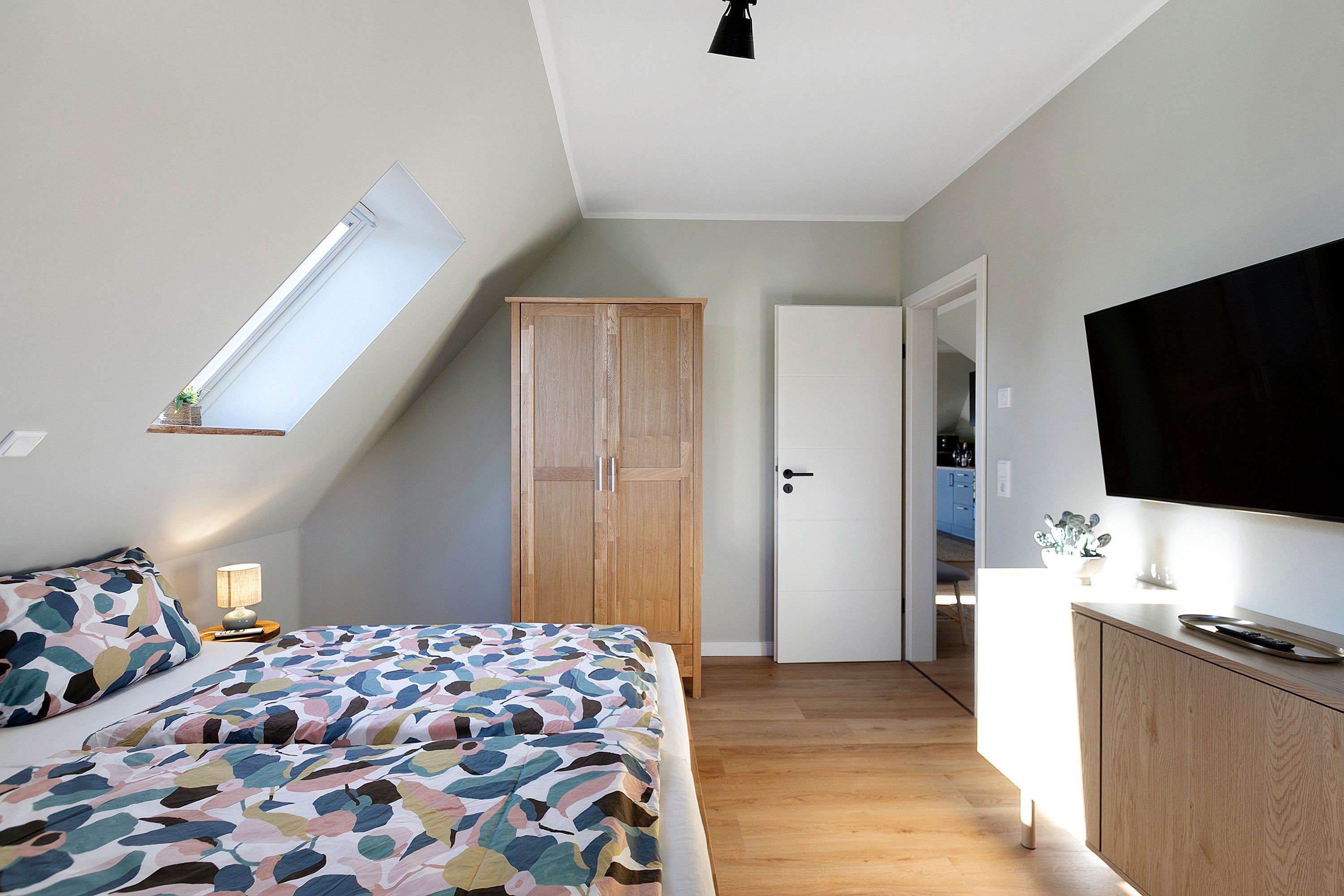 Une chambre à coucher avec un lit, une armoire, une télévision et une lucarne.
