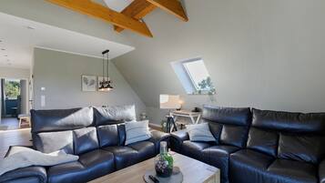 Un salon moderne avec un ensemble de canapés en cuir, une table basse en bois et une lucarne.