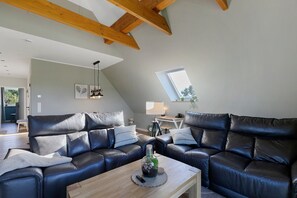 Een moderne woonkamer met een leren zithoek, een houten salontafel en een dakvenster.
