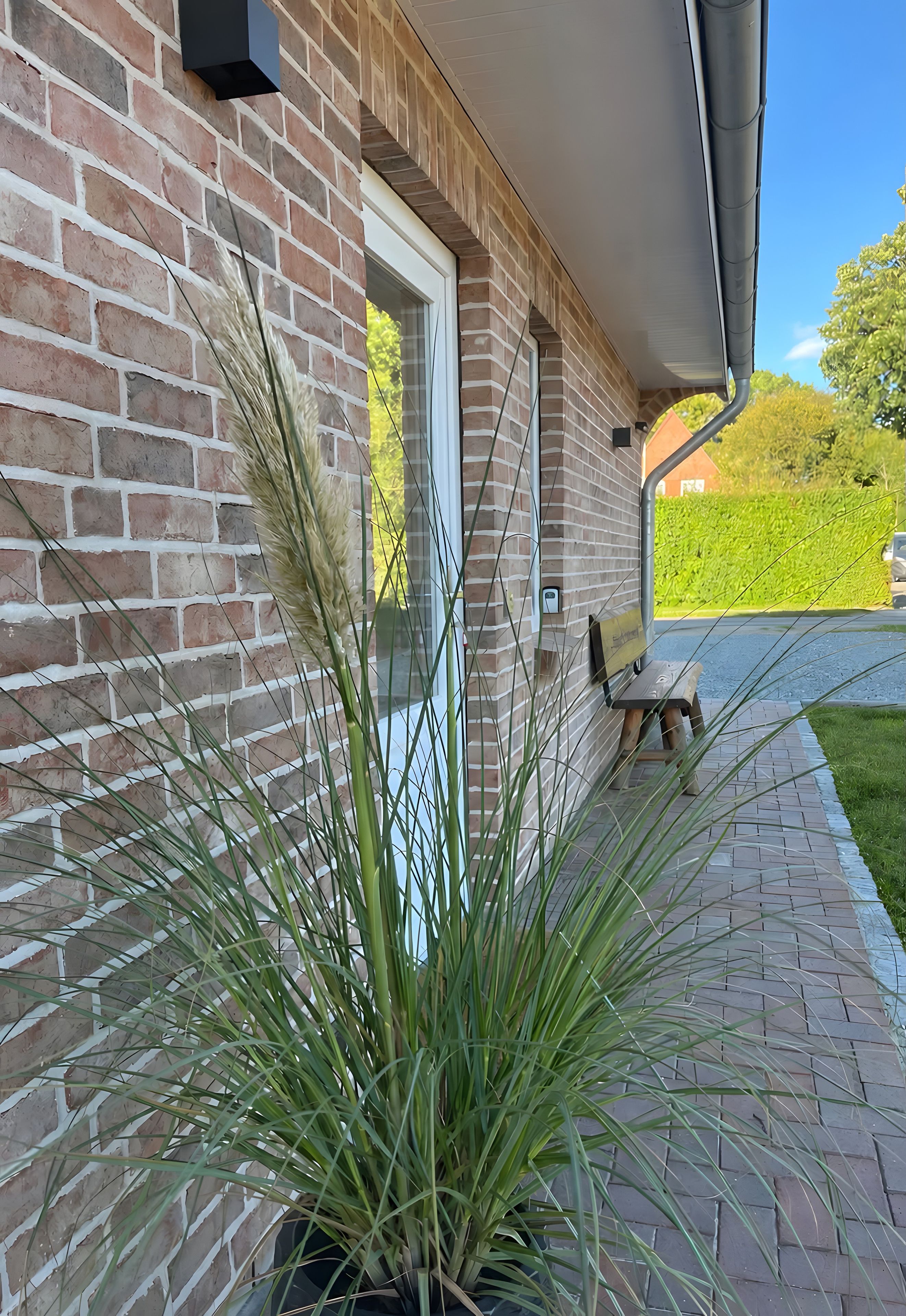 Un bâtiment en briques avec une porte, un pot de fleurs et un banc.