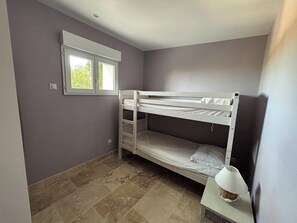 A single-bed room with a window, a lamp on a bedside table, and a tiled floor. - A quiet little corner of paradise (Ceyreste)