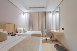 Una habitación de hotel moderna con dos camas, un escritorio y un amplio ventanal con cortinas.