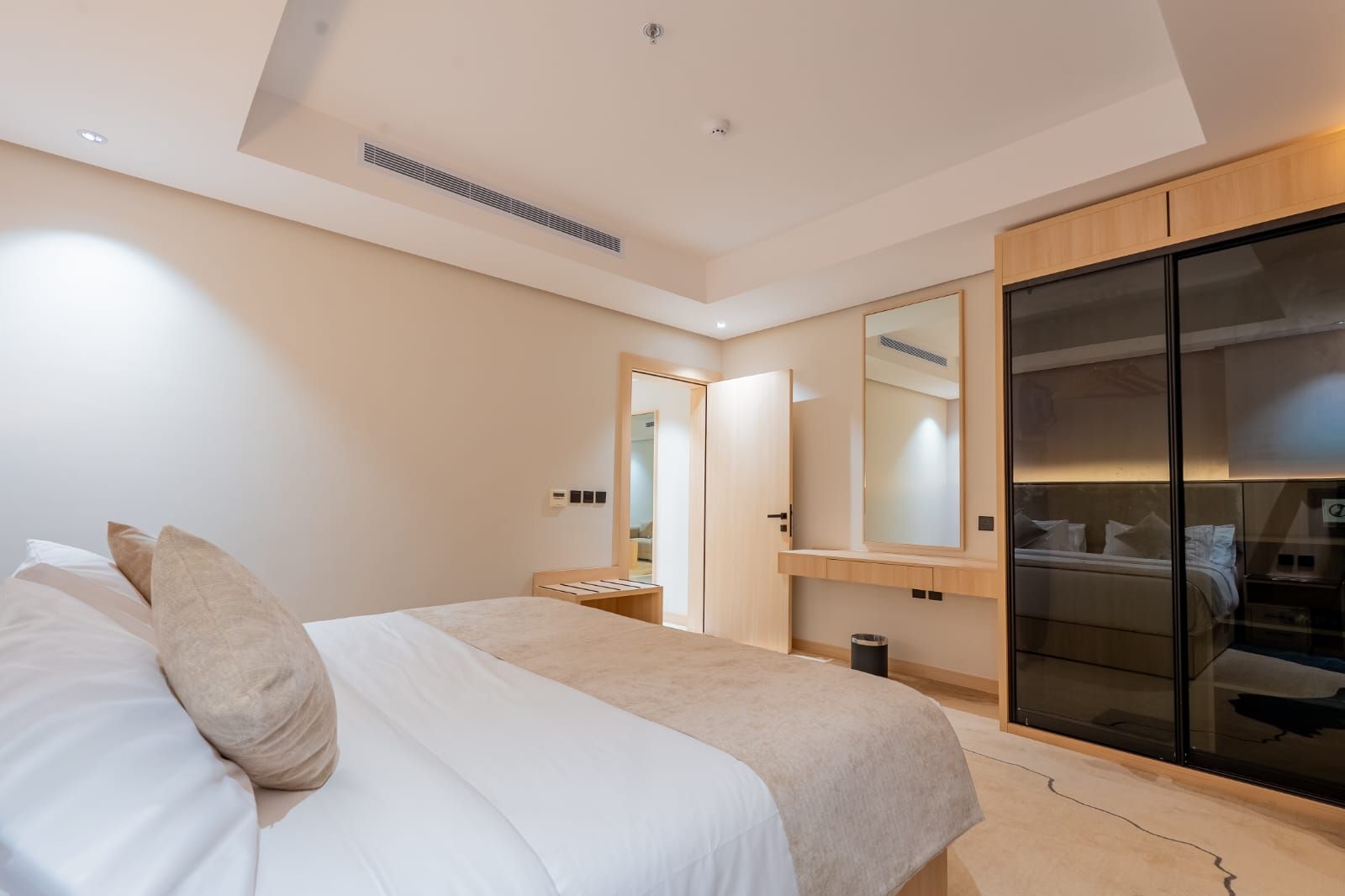 A modern bedroom with a bed, a wardrobe, and a mirror.