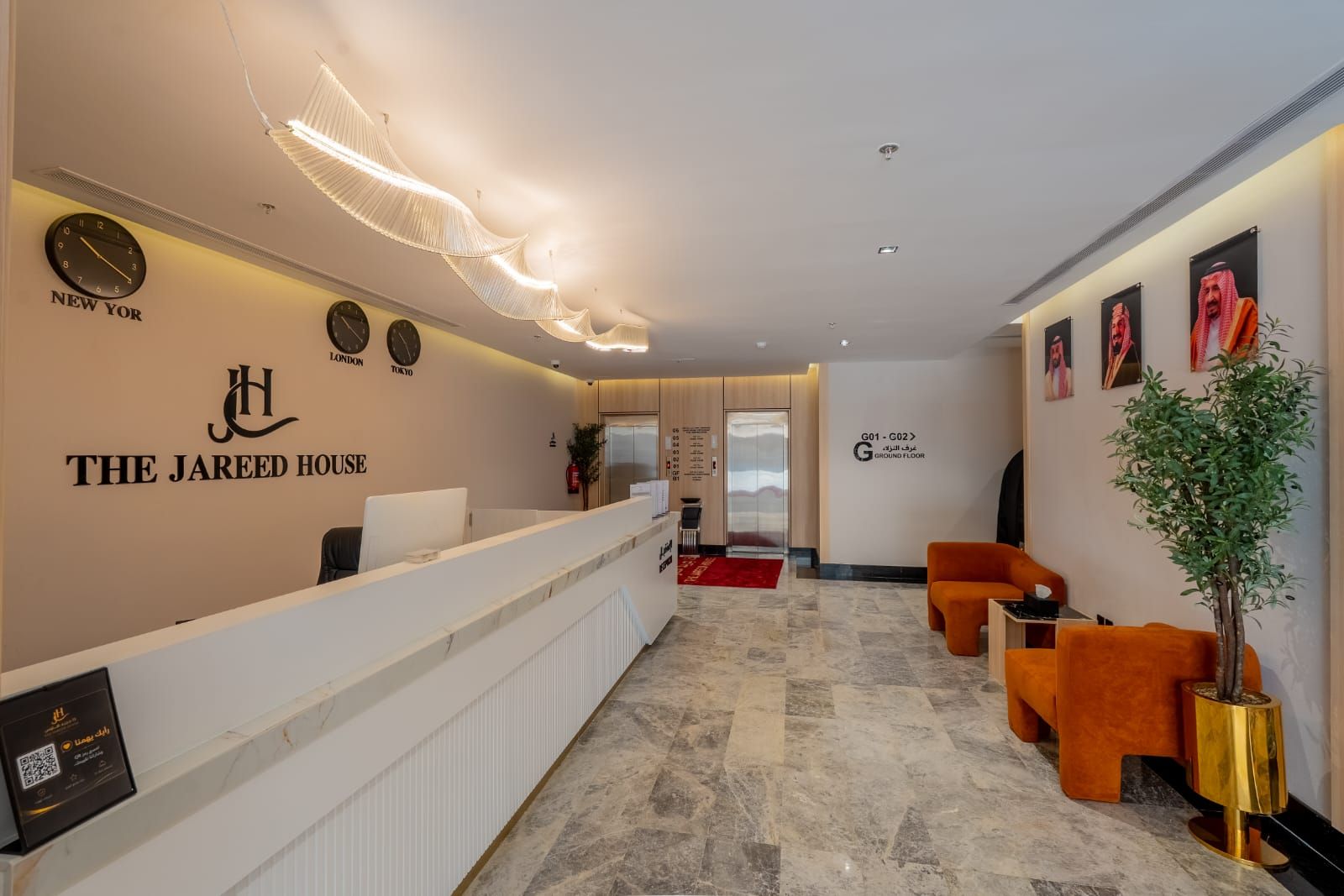 A hotel reception area with a reception desk, seating area, and a wall-mounted clock.