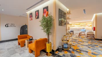 Un vestíbulo de hotel con asientos, una recepción y una barra de café.