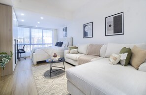 A modern living room with a large sofa, a smaller sofa, a coffee table, and a chair. There are two framed artworks on the wall. - Himalaya Heights View Palace Apartment (Nairobi)