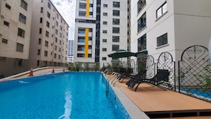 An indoor swimming pool with lounge chairs and a sunshade, surrounded by apartment buildings. - Himalaya Heights View Palace Apartment (Nairobi)