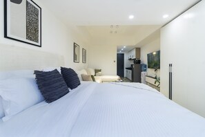 A modern hotel room with a large bed, a kitchenette, a seating area, and artwork on the walls. - Himalaya Heights View Palace Apartment (Nairobi)