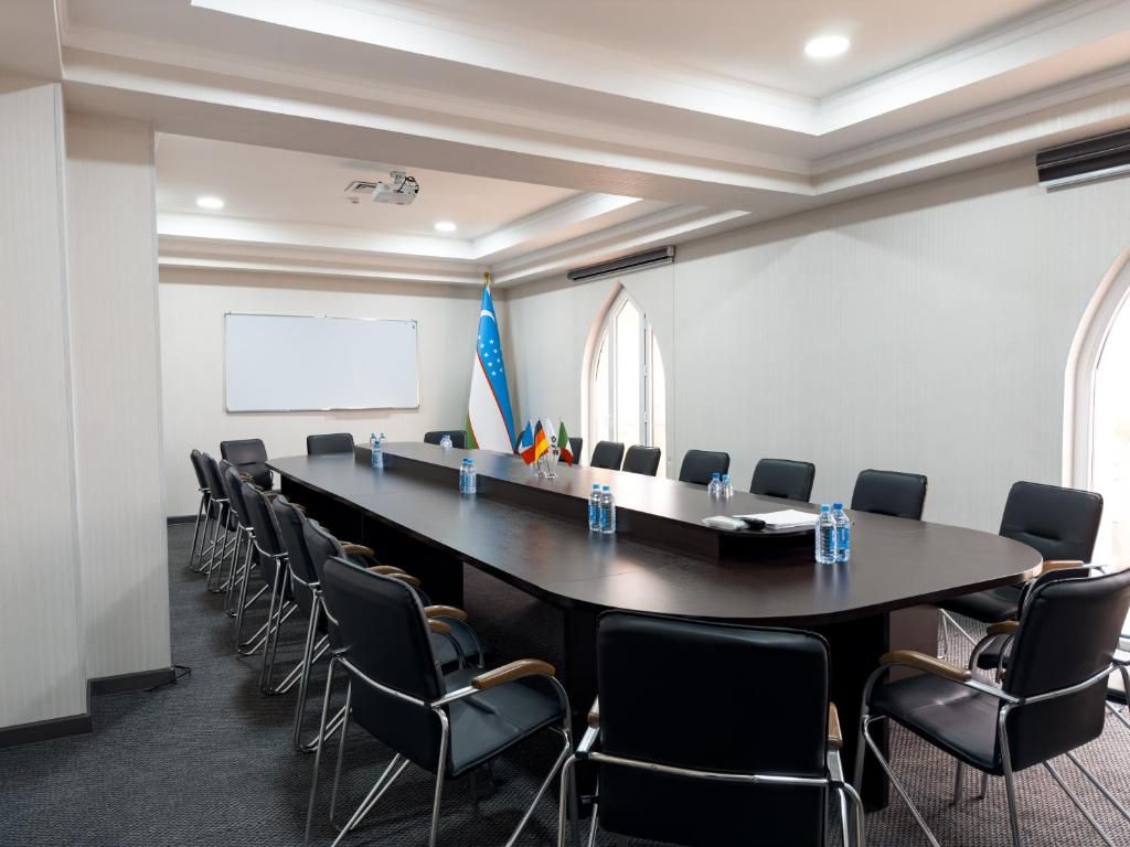 A conference room with a long table, chairs, a whiteboard, and flags.