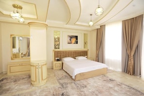A bedroom with a bed, bedside tables, a mirror, a dresser, and a ceiling light fixture. - Amirun Hotel by Reikartz (Tashkent)