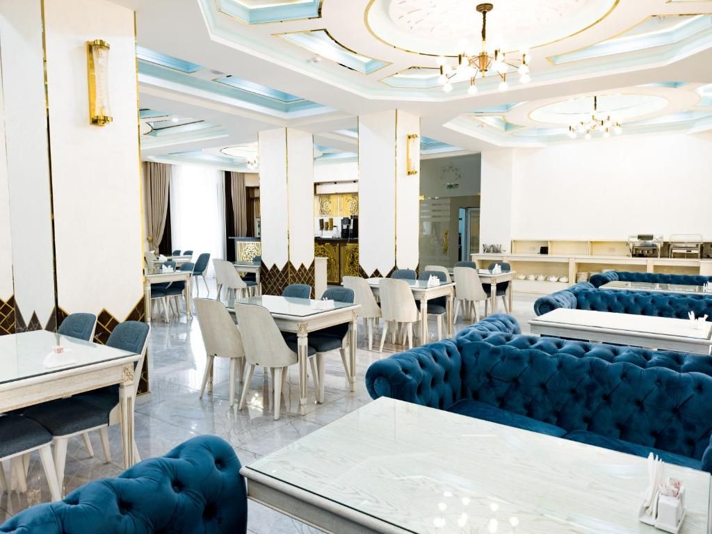 A modern dining area with round tables, blue upholstered booths, and a chandelier.