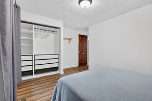 Een slaapkamer met een bed, een kledingkast en een deur.