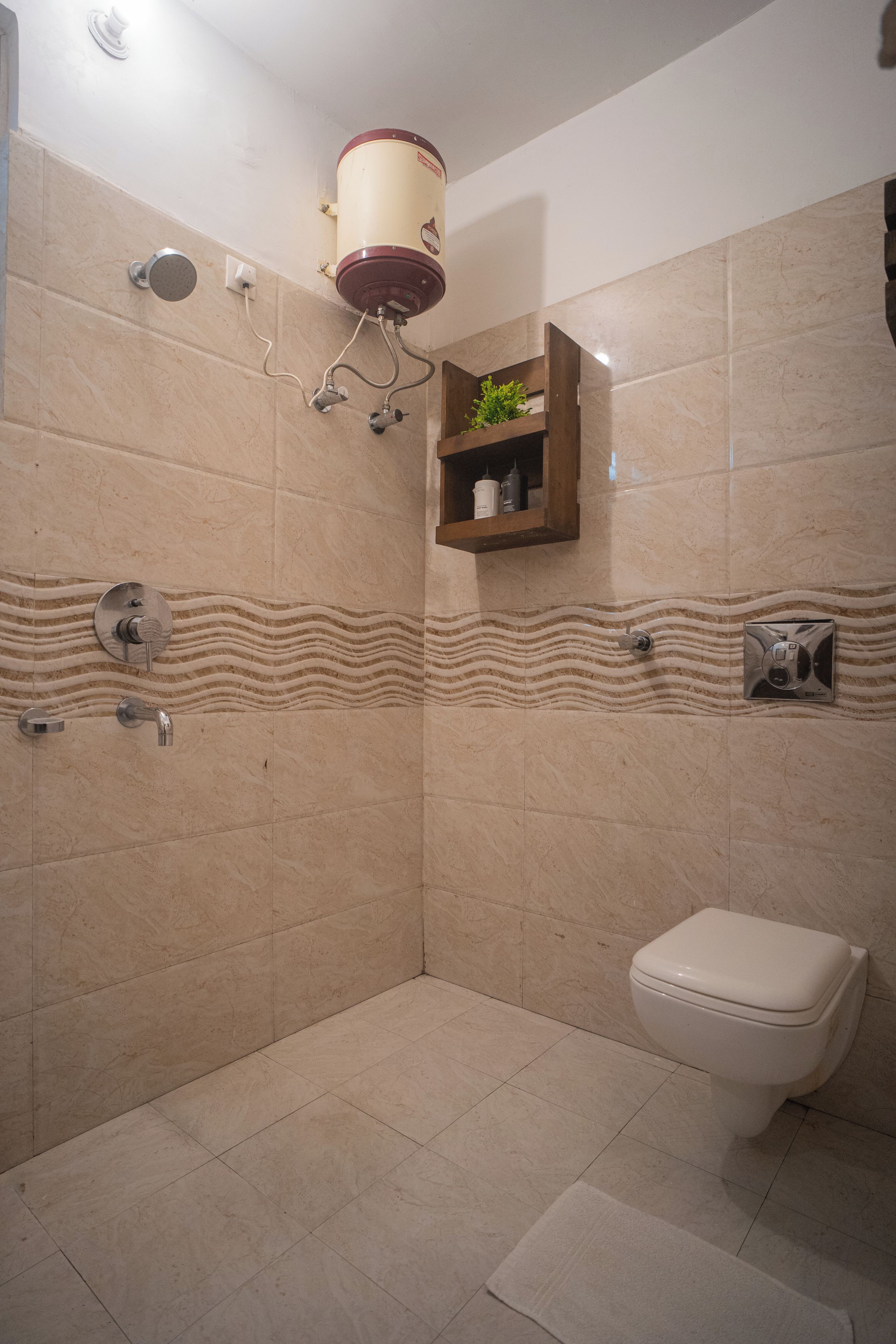 A bathroom with a shower, toilet, and a shelf with toiletries.