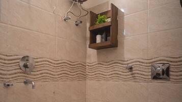 A bathroom with a shower, toilet, and a shelf with toiletries.