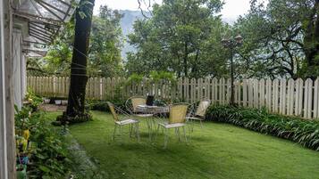 A patio with a table and chairs, surrounded by a wooden fence and lush greenery.