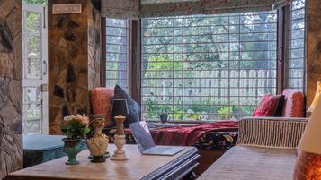 Una habitación acogedora con pared de piedra, un ventanal con vistas a la vegetación, una mesa con una computadora portátil y un globo decorativo.