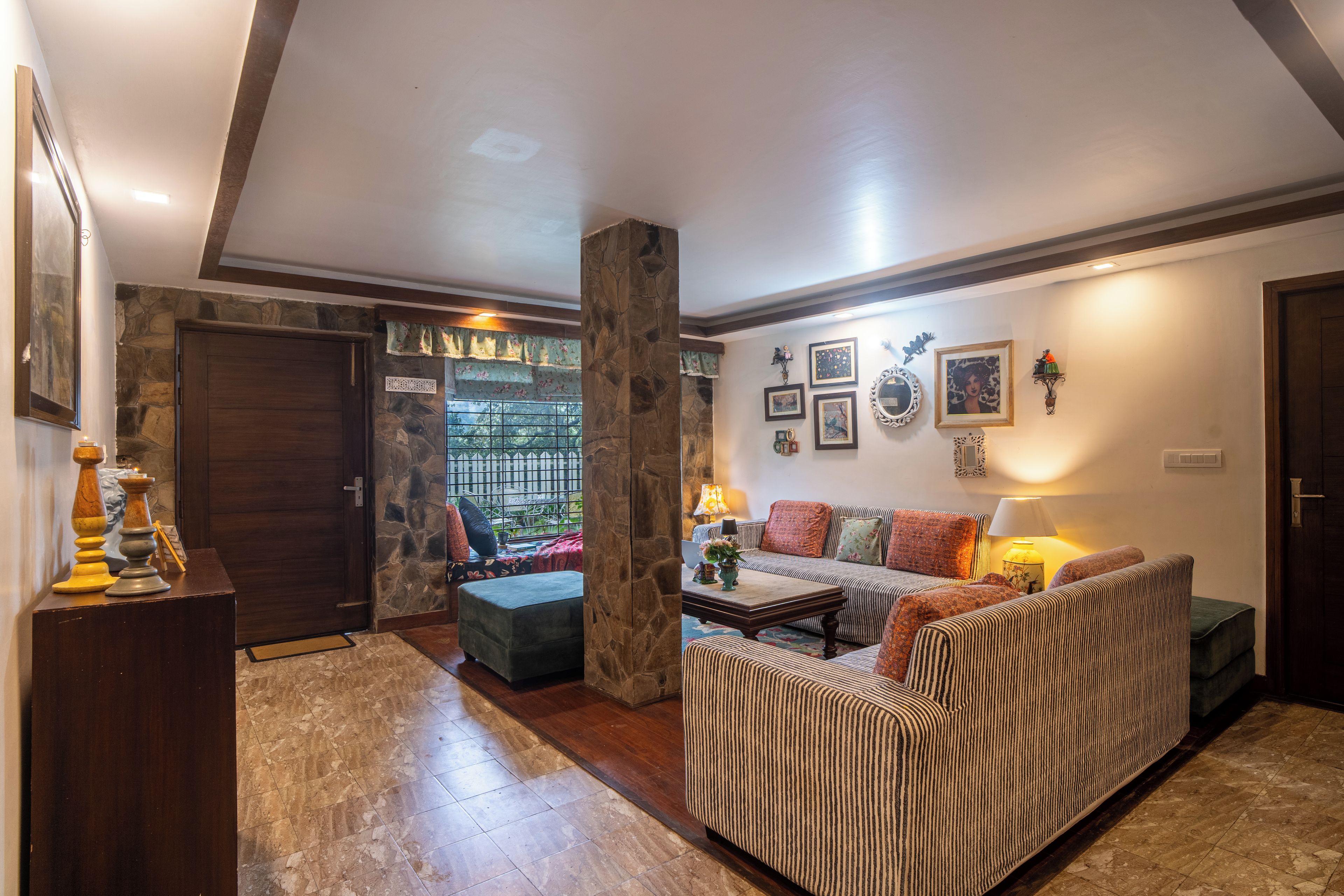 A living room with a stone fireplace, a sofa, a coffee table, and a dining area with a table and chairs.
