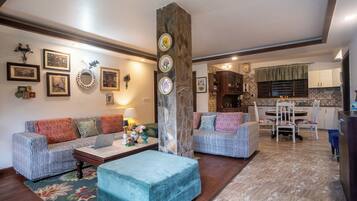 A living room with a sofa, ottoman, and a dining area with a table and chairs.