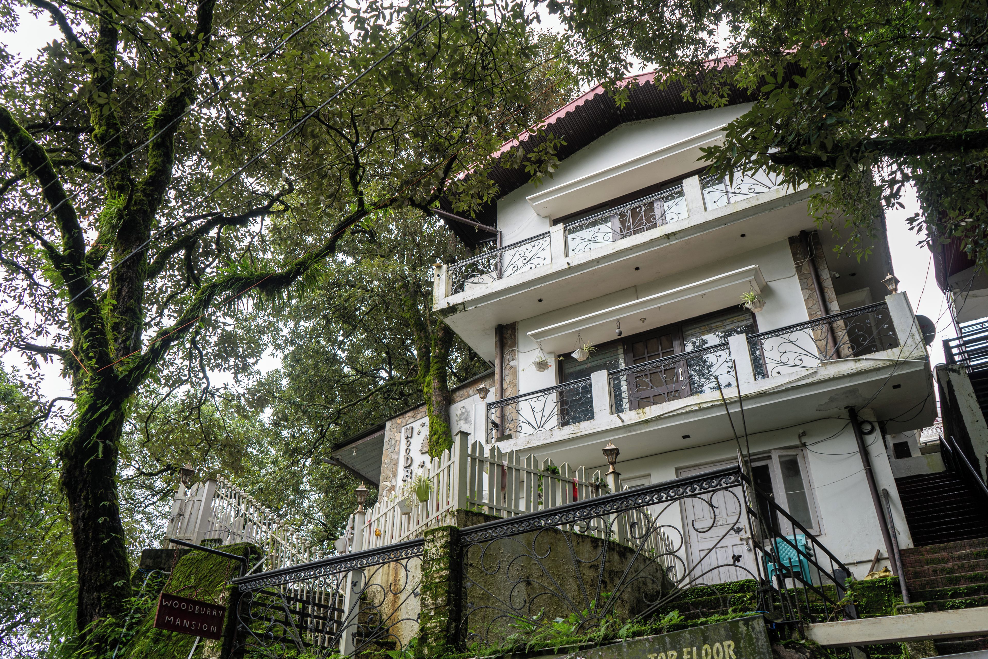 A multi-story building with a stone facade, balconies with metal railings, and a staircase leading to the entrance.