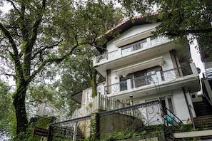 A multi-story building with a stone facade, balconies with metal railings, and a staircase leading to the entrance. - Alaya Stays Woodbury Mansion 3BHK Villa (Nainital)