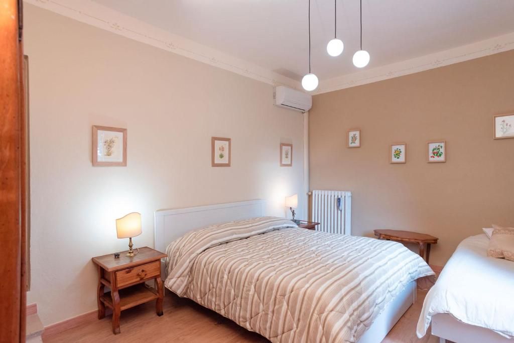 Un dormitorio con cama, mesitas de noche, aire acondicionado instalado en la pared y cuadros enmarcados.