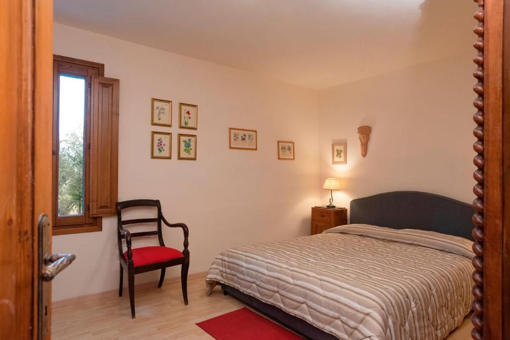 Un dormitorio con cama, una silla, una mesita de noche y cuadros en la pared.
