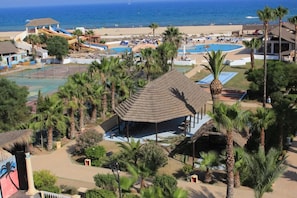 Un complejo turístico con piscina, playa y parque acuático.