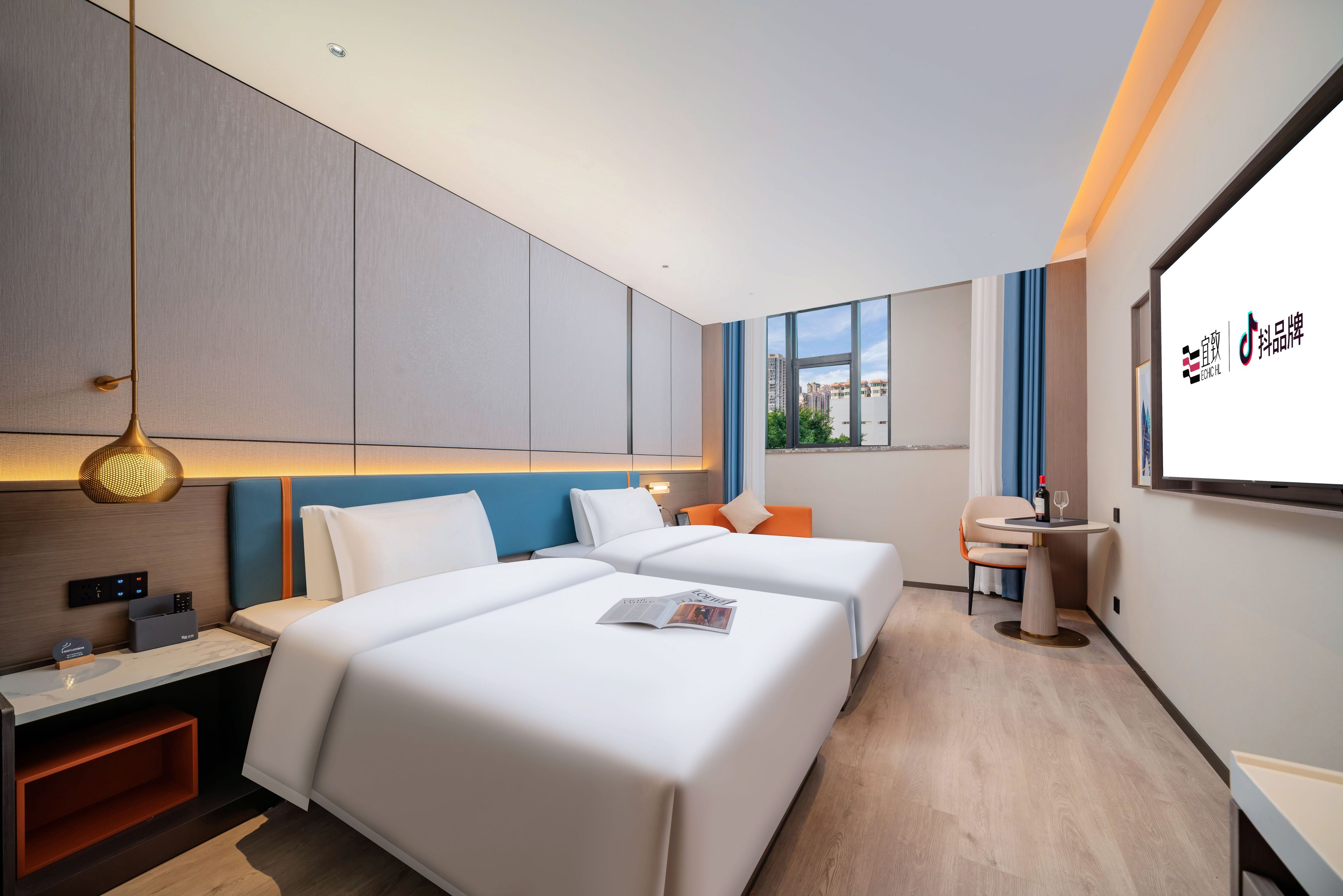 Habitación de hotel con dos camas, un escritorio, una silla, un televisor y una ventana con vistas a la ciudad.