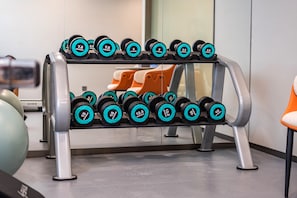 A weightlifting rack with dumbbells of various weights.