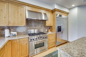 A kitchen with wooden cabinets, a stainless steel stove, and a refrigerator. - Sun Valley Extended Stay: Central Condo w/ Patio (Ketchum)