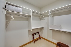 A walk-in closet with open shelves, a hanging rod, and a small wooden stool. - Sun Valley Extended Stay: Central Condo w/ Patio (Ketchum)