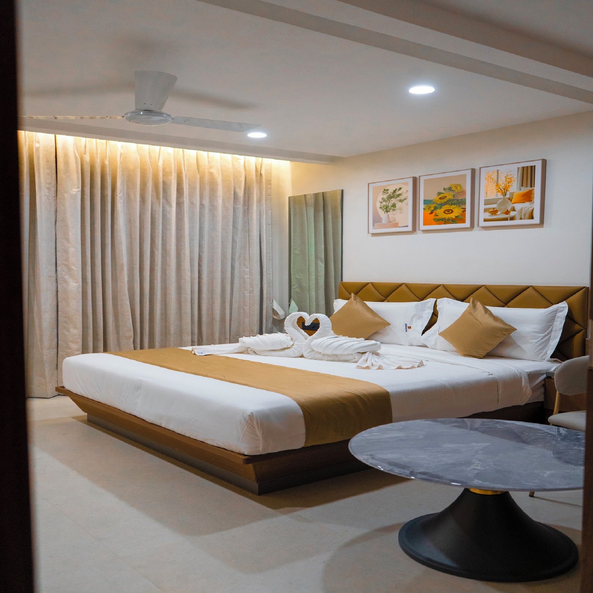 Una habitación de hotel con una cama, una mesa redonda y un ventilador de techo.