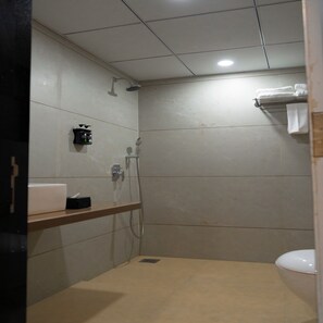 Un baño pequeño con azulejos, una ducha, un inodoro y un estante con artículos de aseo.