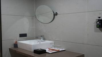 Un baño moderno con un lavabo rectangular, un espejo redondo y un dispensador de jabón.
