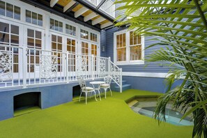 A covered outdoor area with a blue wall, white railing, and green artificial grass. - 5 Mi to UF! Luxury 2-Unit Combo w/ Hot Tub (Gainesville)