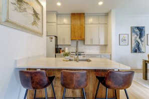 A modern kitchen with a large island, bar stools, and wooden accents. - 5 Mi to UF! Luxury 2-Unit Combo w/ Hot Tub (Gainesville)