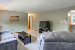 A living room with a flat-screen TV, a coffee table, and a sofa.