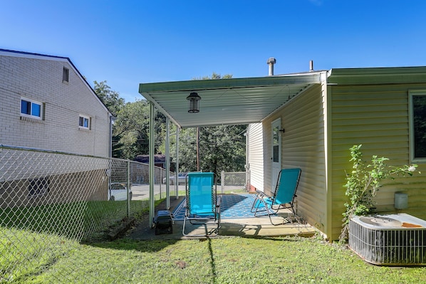 A covered patio area with a pool, two chairs, and a small table.