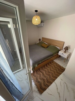 Ein Schlafzimmer mit einem Bett, einem Nachttisch, einer Lampe, einer Pendelleuchte und einer Tür.