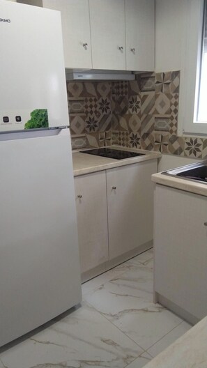 Eine Küche mit Kühlschrank, Spüle und Fliesenspiegel mit Muster.