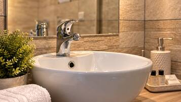 A bathroom with a white sink, a mirror, and a wooden countertop.