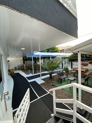 A covered outdoor seating area with tables and chairs, surrounded by potted plants and a white fence. - GalyRod House Hotel (San Andrés)